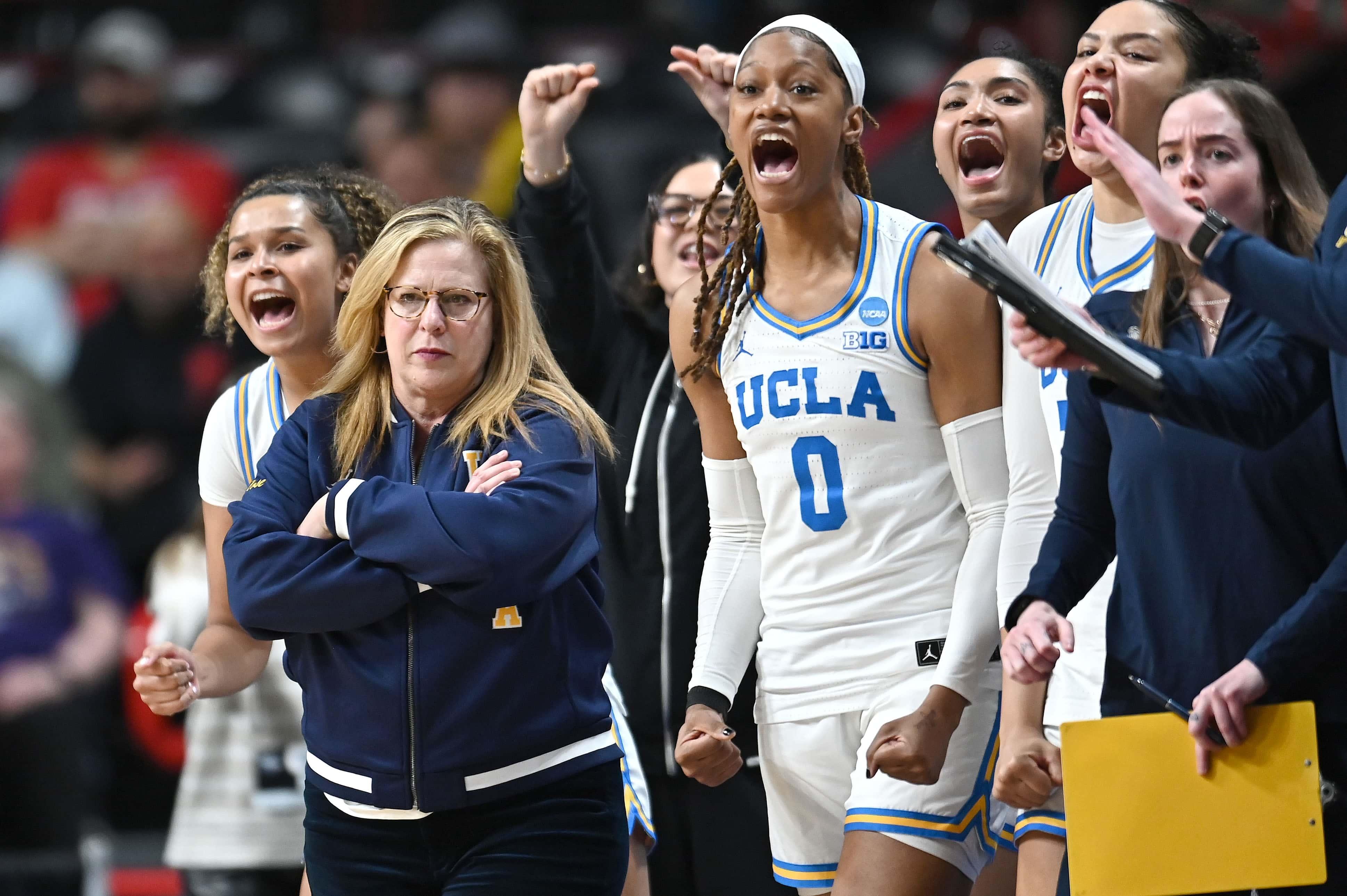 A women's basketball team celebrates from the sideline. 